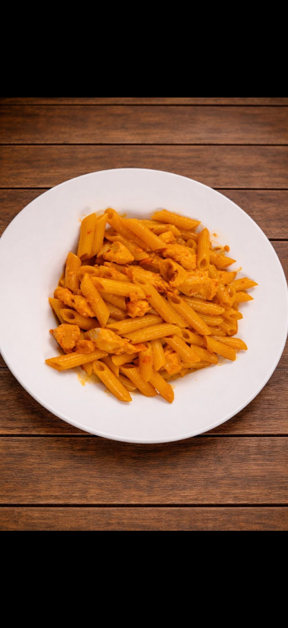 Chicken Mozambique tossed with penne pasta in a warm orange sauce